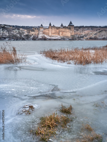 cold day on the river with view to the medieval castle behind frozen river in cloudy day