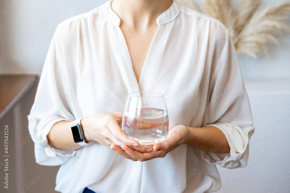 Woman in white blouse holding glass of water. Hydration and water balance concept. Woman in white blouse holding glass of water. Hydration and water balance concept.