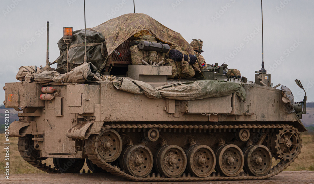 british army FV430 in motion, fully loaded with troop bergens under a tarpaulin cover 