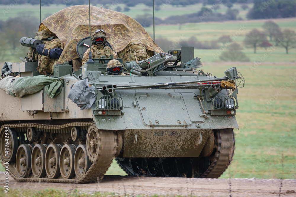british army FV430 in motion, fully loaded with troop bergens under a tarpaulin cover 