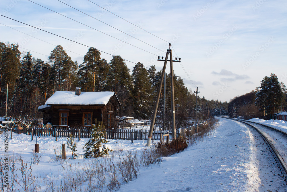 Snow-covered old traditional village hut at the edge of the forest by the railway in the Ulyanovsk region in Russia on a winter day. Traditional Russian winter landscape. Snow-covered old traditional village hut at the edge of the forest by the railway in the Ulyanovsk region in Russia on a winter day. Traditional Russian winter landscape.