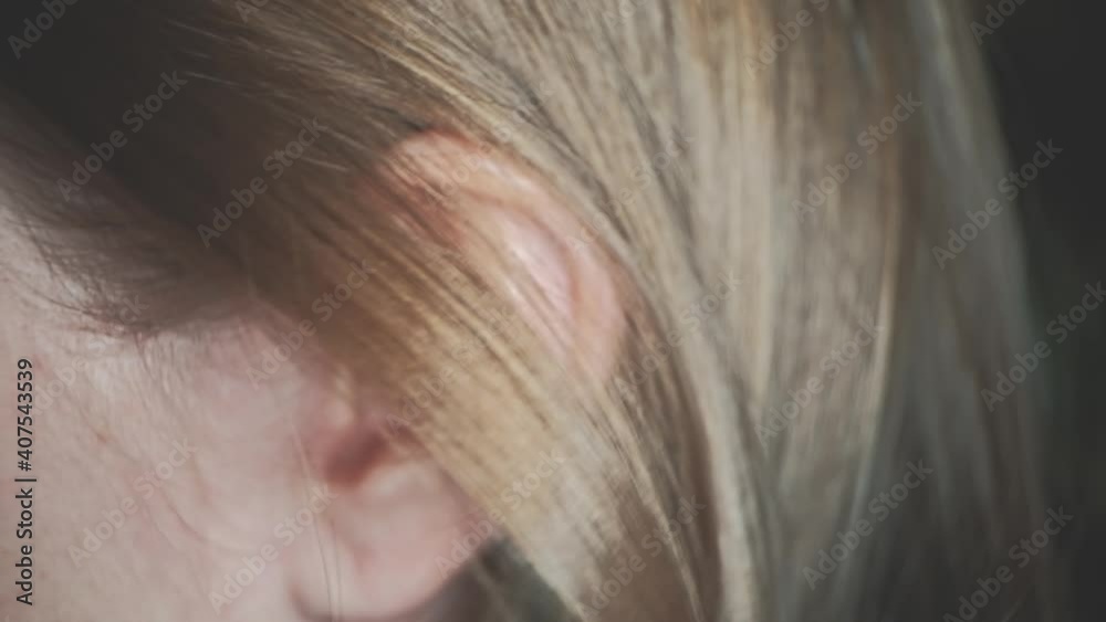 Young caucasian woman ear closeup. She is opening ear by her hand with jevelry rings Young caucasian woman ear closeup. She is opening ear by her hand with jevelry rings