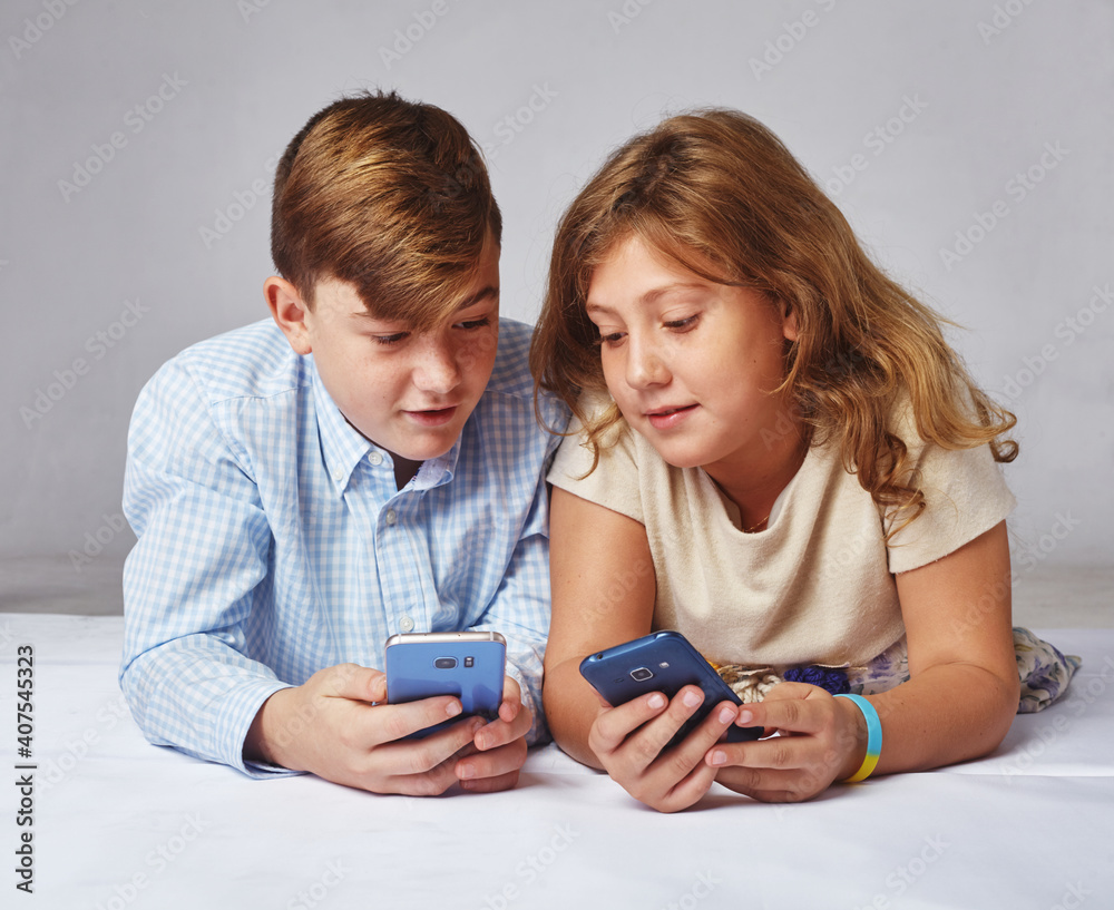 young girl and a boy playing in the phone, smiling and laughing. Children learn new technologies young girl and a boy playing in the phone, smiling and laughing. Children learn new technologies