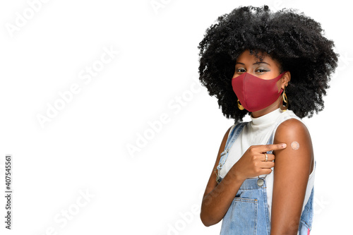 girl points to the vaccine patch on her arm, Dark-skinned teen girl points the sticker   on the arm shows she was vaccinated, wearing face protection mask, sars-cov-2 covid-19 photo