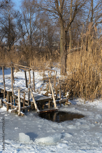 An ice-hole on a frozen river. Place for dipping. Ice bathing concept. Vertical orientation.