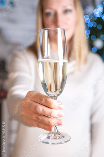 a girl in a white sweater holds a glass of sparkling wine on her outstretched hand