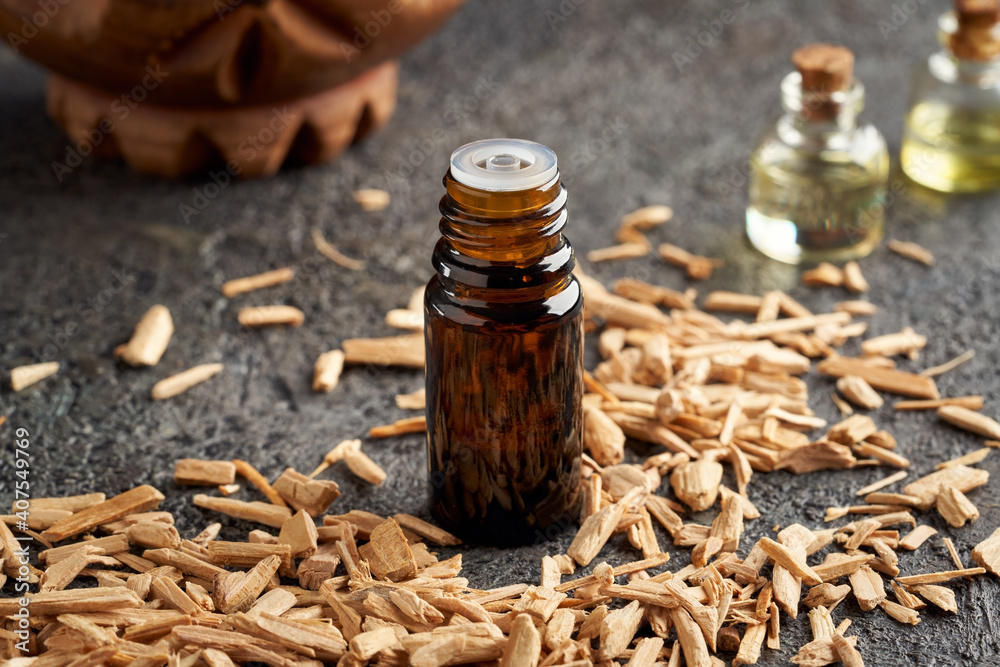 A dark bottle of essential oil with cedar wood chips A dark bottle of essential oil with cedar wood chips