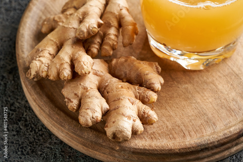 Fresh ginger root on a wooden cutting board, with natural probiotic drink containing ginger