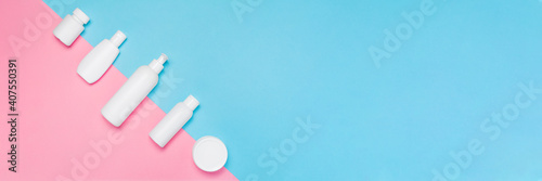 Banner with white cosmetic bottles mockup on pink and blue background. Tubes, dispensers and jars. Branding identity concept. Flat lay with copy space
