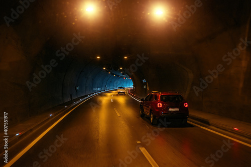 Road tunnel in mountain illuminated by lamps