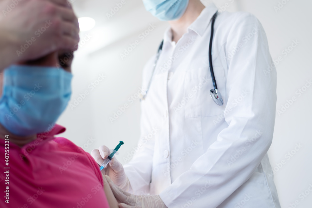 Young Female doctor in protective mask injecting or prepairing for injecting vaccine against coronavirus or ncov 19 or covid into patient's arm Young Female doctor in protective mask injecting or prepairing for injecting vaccine against coronavirus or ncov 19 or covid into patient's arm