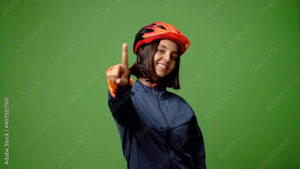 Young woman with cycling helmet showing and lifting a finger in sign of the best Young woman with cycling helmet showing and lifting a finger in sign of the best