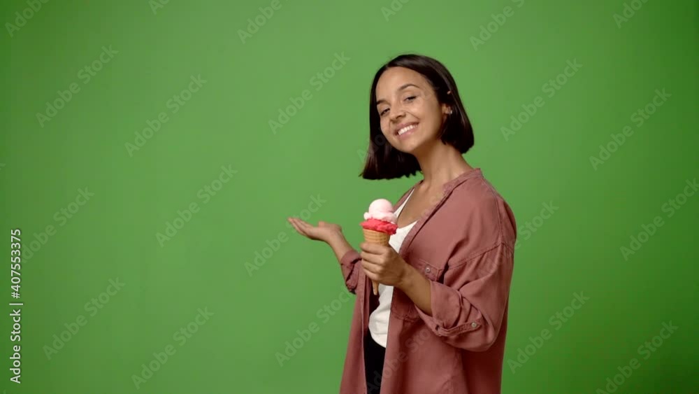 Young woman holding a cornet ice cream pointing back and presenting a product Young woman holding a cornet ice cream pointing back and presenting a product