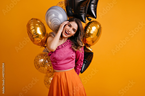 Attractive dark-haired woman celebrating birthday. Interested white lady posing with party balloons.