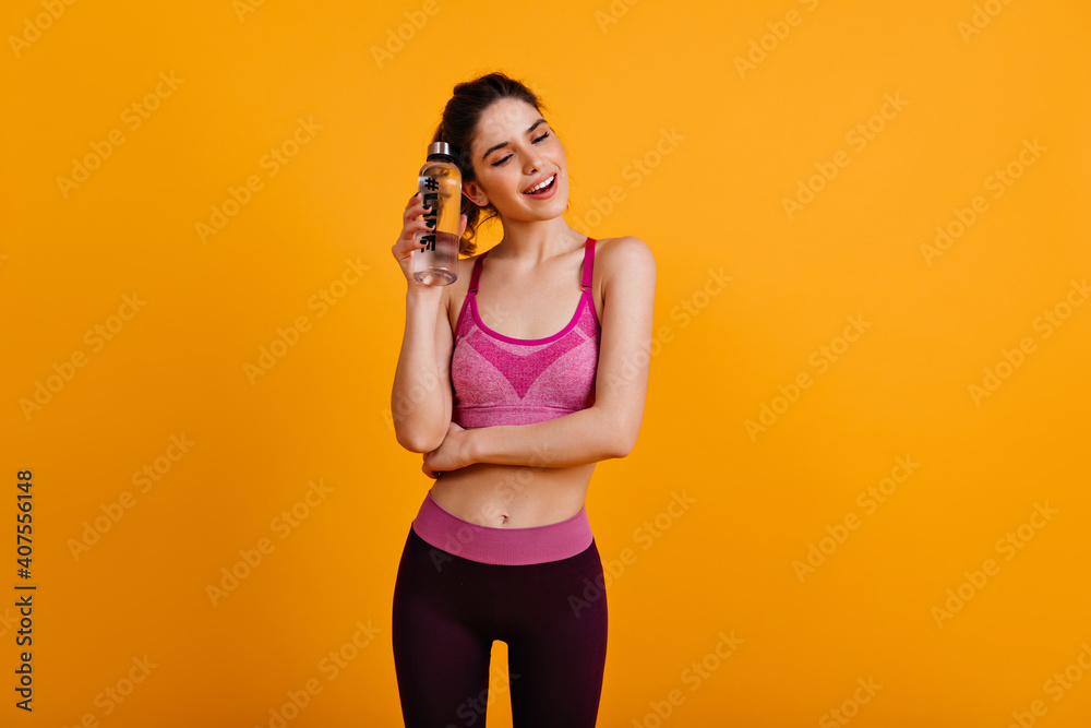 Pretty girl in good shape standing on yellow background. Sporty woman posing after training. Pretty girl in good shape standing on yellow background. Sporty woman posing after training.