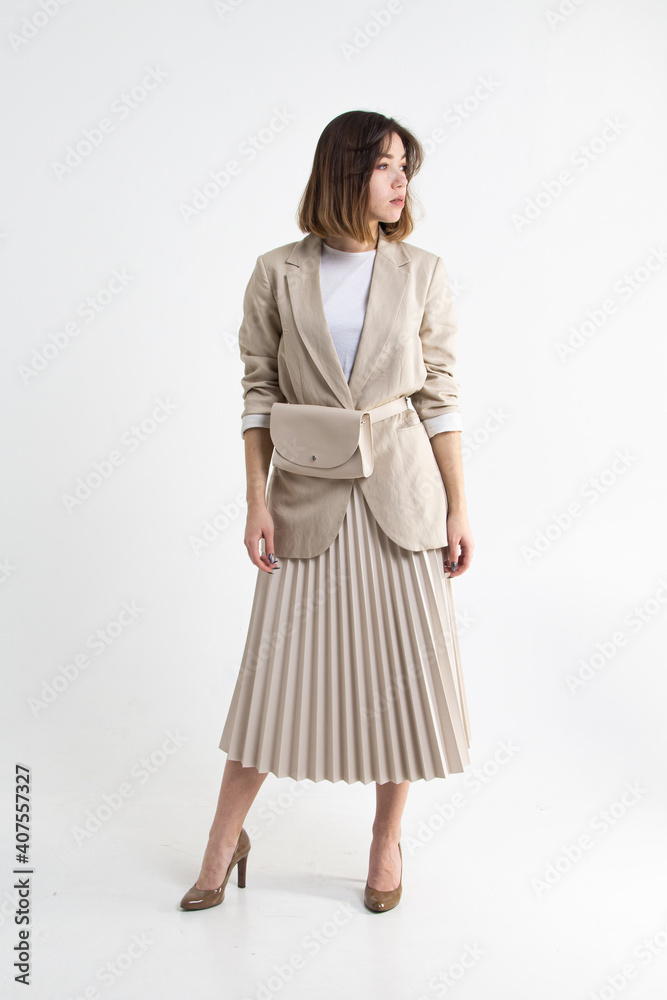 Young attractive woman in light beige jacket and skirt. Young business woman on white background Young attractive woman in light beige jacket and skirt. Young business woman on white background