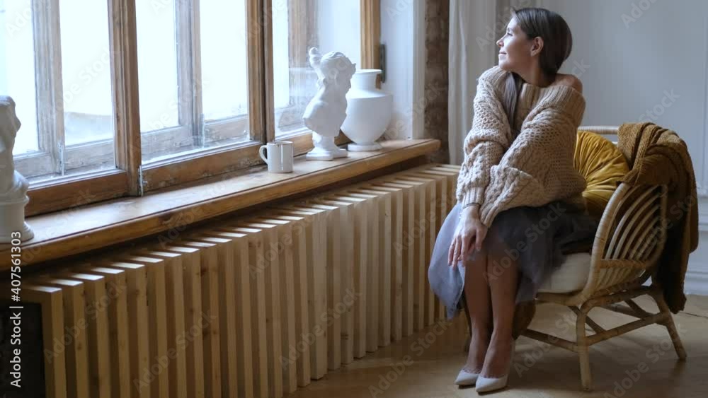stylish woman sitting in a chair at home by the window
