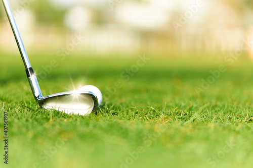 Golf clubs and golf balls on a green lawn with beautiful sunlight.