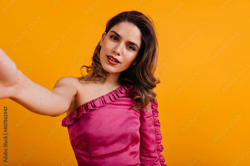 Elegant woman in pink blouse making selfie. Portrait of fashionable lady isolated on yellow. Elegant woman in pink blouse making selfie. Portrait of fashionable lady isolated on yellow.
