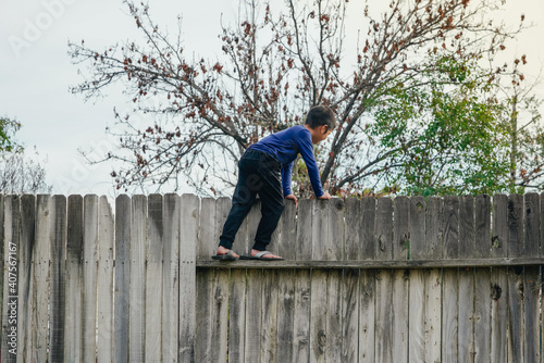 The boy climbed the fence to greet the neighbors.