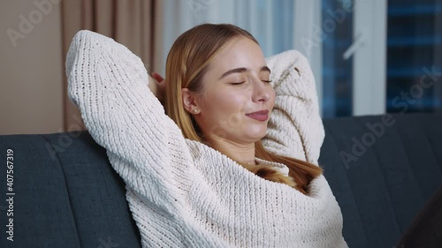 Calm young woman having nap relaxing on couch with eyes closed hands behind head sitting on sofa at home. Life satisfaction. Dream mood. Sleep. Slow motion