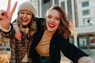 Cheerful female friends enjoying autumn. Pleasant caucasian girls having fun outdoor.