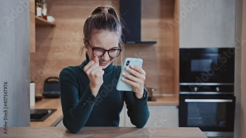 Close up young woman with glasses use phone. Feel happy smiling sitting near table. Message texting workplace smartphone browsing internet device. Slow motion