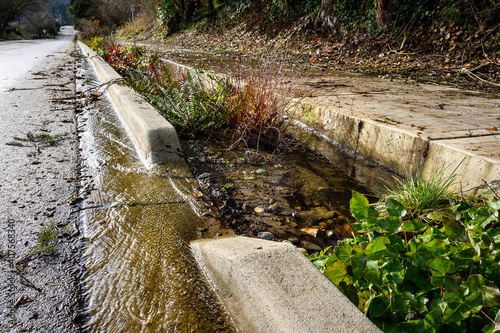 Foto After the storm, floodwater running down the garden median on a sunny day
