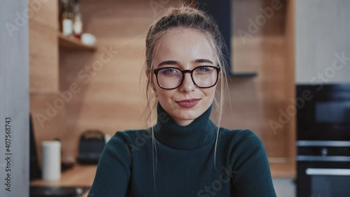 Beautiful stylish young woman in glasses looking at camera on home. Feel happy. Carefree confidence youth. At kitchen room. Portrait. Close up. Slow motion