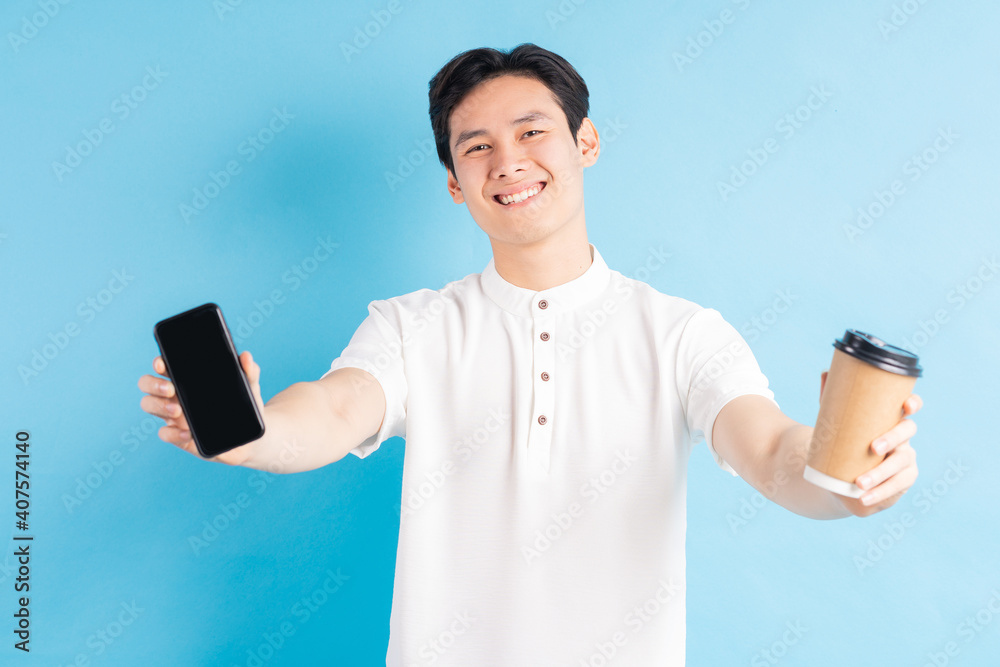 A photo of a handsome Asian man holding his phone and paper cup in his hand A photo of a handsome Asian man holding his phone and paper cup in his hand