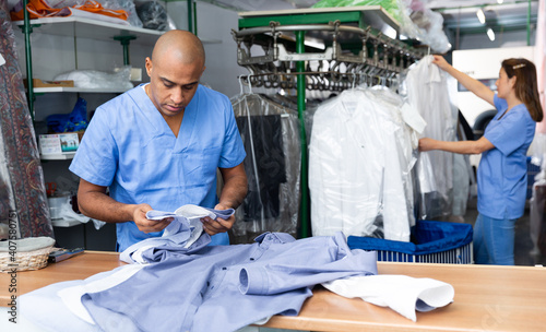 Portrait of skilled male laundry worker examining clean garments