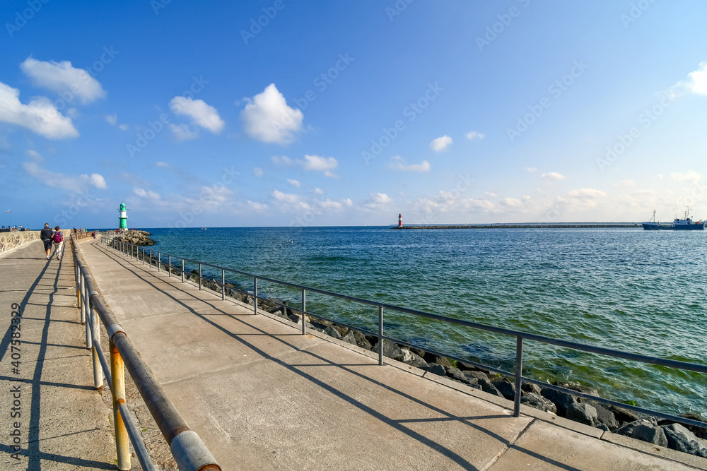 Two lighthouses, one green and one red are visible from the promenade boardwalk along the Baltic Sea coast at the town of Warnemunde, Germany.