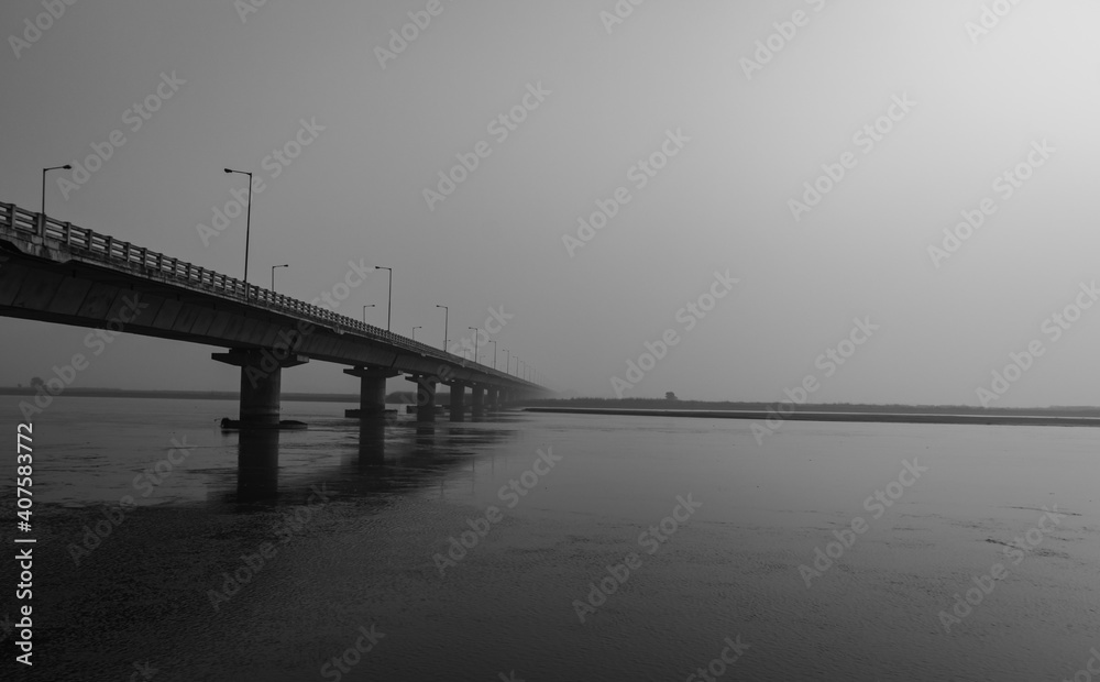 road bridge over river with its water reflection at dawn from low angle black and white