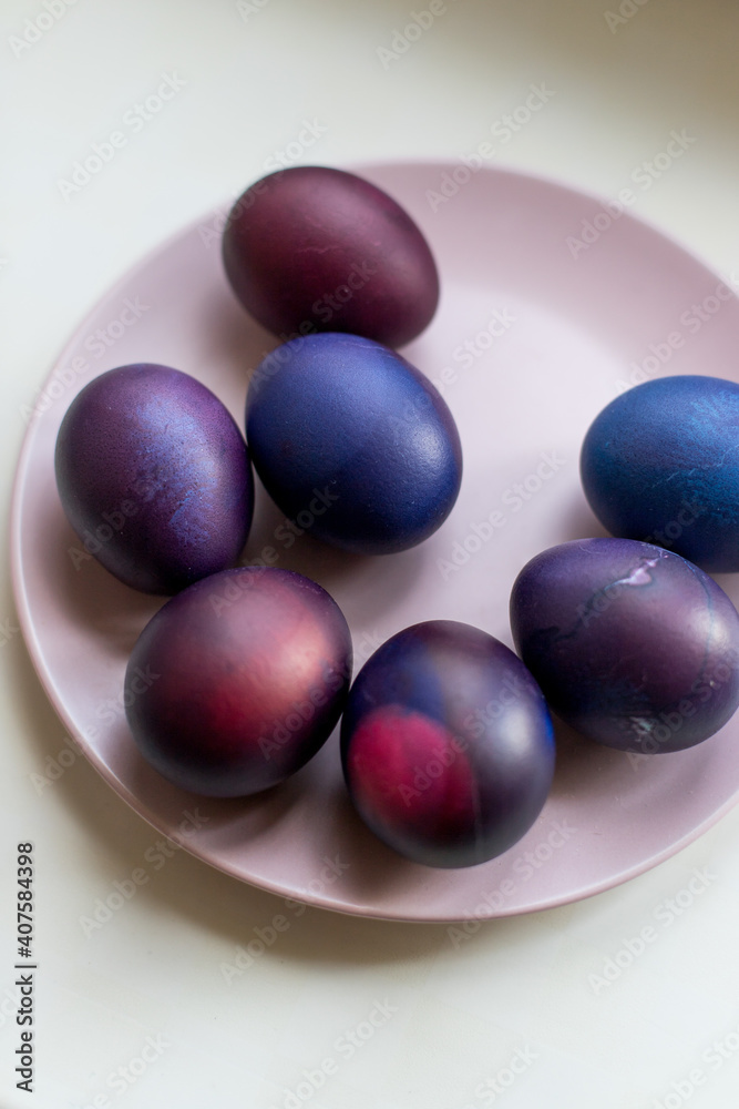 Painted blue and purple Easter eggs on a textured background. Easter eggs on a plate. Painted blue and purple Easter eggs on a textured background. Easter eggs on a plate.