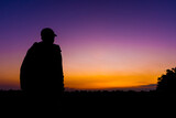 silhouette dark young man wearing a hat standing emotions with evening Twilight sky with cloud in the winter season at sunset Abstract background.Copy space for your