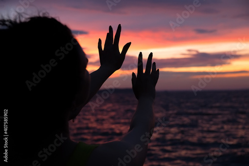 Beautiful woman silhouettes against the background of the sea and evening sunset.