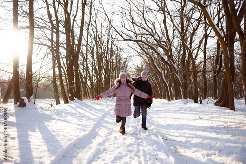 Brother and sister run through the snowy forest. Winter activities for children. Frost, snow and rest.