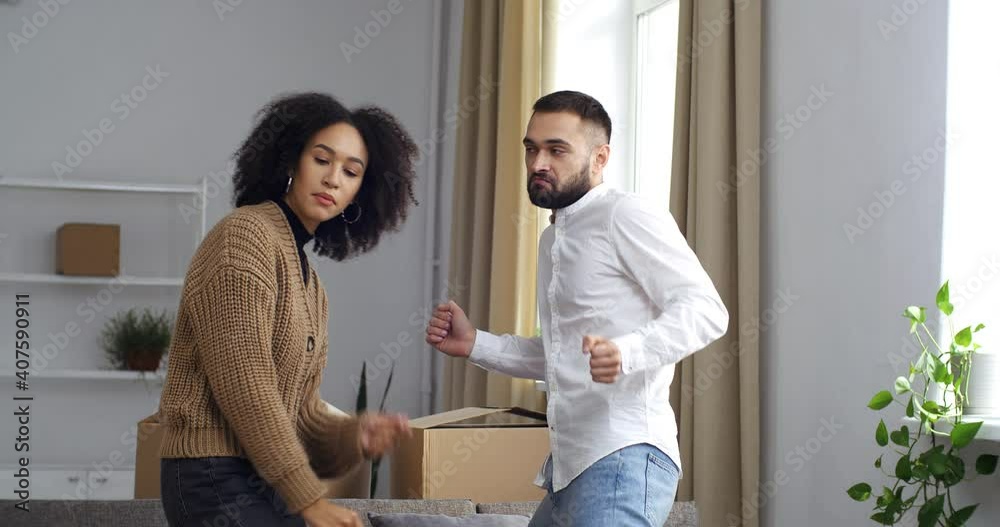 Couple friends multinational family Afro American woman and Caucasian man dancing surrounded by cardboard boxes rejoicing move celebrating new stage of life collecting things enjoying moving to music Couple friends multinational family Afro American woman and Caucasian man dancing surrounded by cardboard boxes rejoicing move celebrating new stage of life collecting things enjoying moving to music