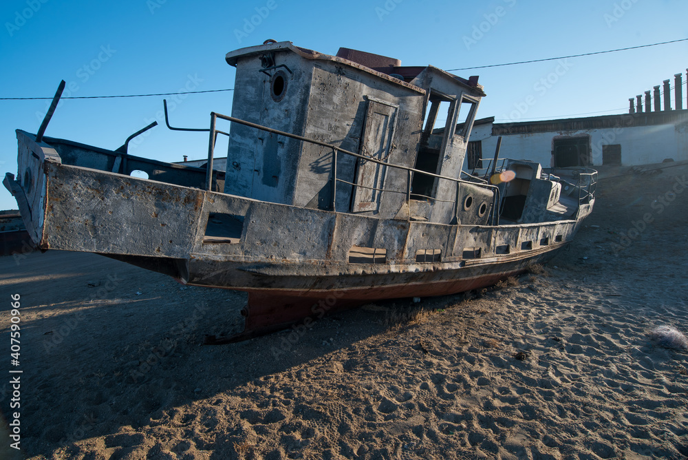 a rusty old ship sits in the ice of a frozen lake