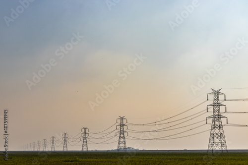 electricity pole with high tension power transmission cable in green fields of countryside area © explorewithinfo