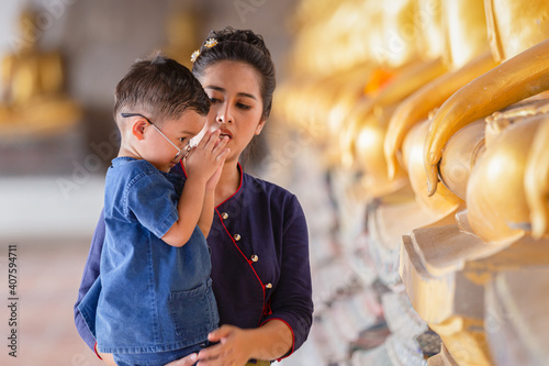 Mother and son praying respect buddha statue in Wat Phutthai Sawan Temple, Ayutthaya, Thailand photo