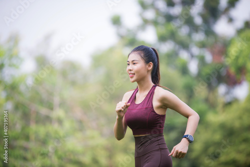 Asian Young female athlete jogging in forest. Jogger doing morning physical training.