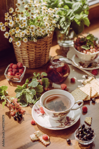 summer breakfast. a summer garden still life with a mug of tea, wildflowers and berries. garden aesthetics