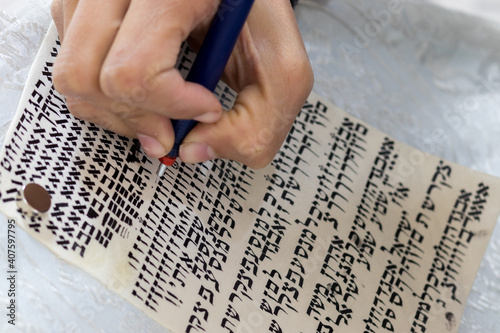 A writer's hand practices decorating letters from a Torah scroll written on parchment in Hebrew, (for the editor - the Hebrew letters are random without meaning)