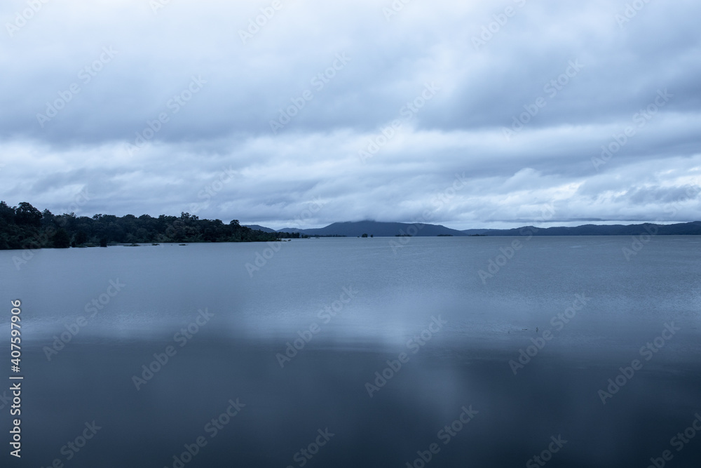 river serene back water with mountain shadow and dramatic cloudy sky long exposure image