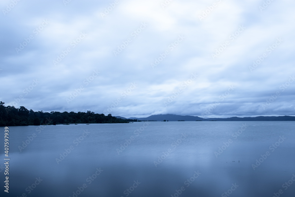Fototapeta premium river serene back water with mountain shadow and dramatic cloudy sky long exposure image