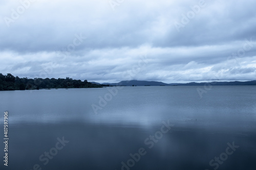river serene back water with mountain shadow and dramatic cloudy sky long exposure image