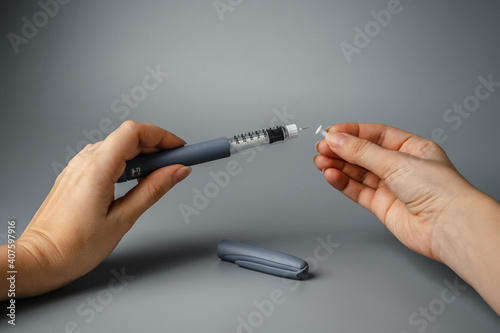 A young woman holds a syringe for insulin. Diabetes is a disease of the endocrine system. Syringe on a gray background.