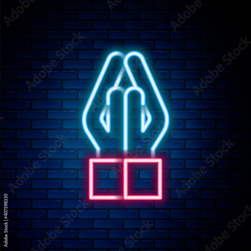 Glowing neon line Hands in praying position icon isolated on brick wall background. Prayer to god with faith and hope. Colorful outline concept. Vector.