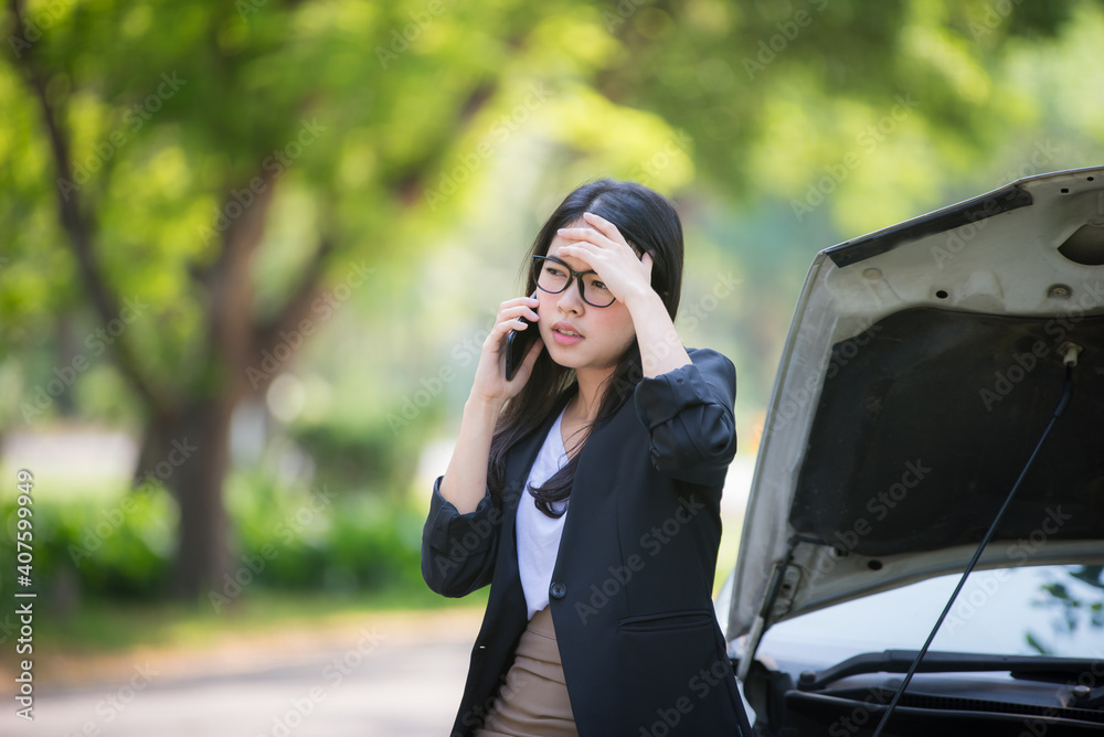 Asian business woman sad waiting for help by a broken car. Use a mobile phone to call the mechanic. Asian business woman sad waiting for help by a broken car. Use a mobile phone to call the mechanic.